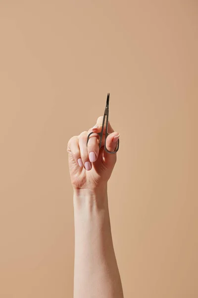 Partial view of female hand with nail scissors isolated on beige — Stock Photo