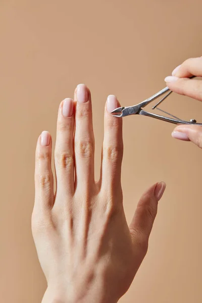 Vista parcial de la mujer usando pinza cutánea aislada en beige - foto de stock