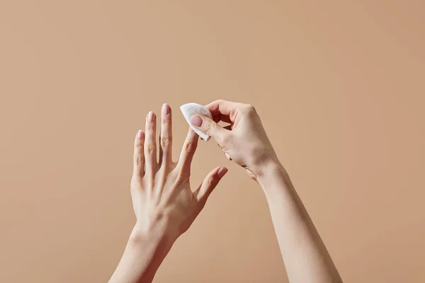 Partial view of woman removing nail polish with cotton pad isolated on beige — Stock Photo