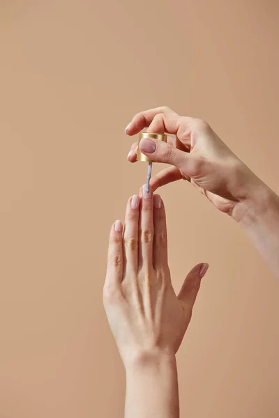 Обрезанный вид женщины, применяющей лак для ногтей изолирован от бежевого цвета — стоковое фото