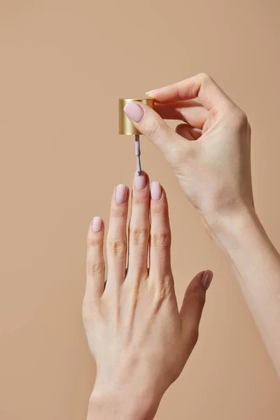 Vista parcial da mulher aplicando esmalte isolado em bege — Fotografia de Stock