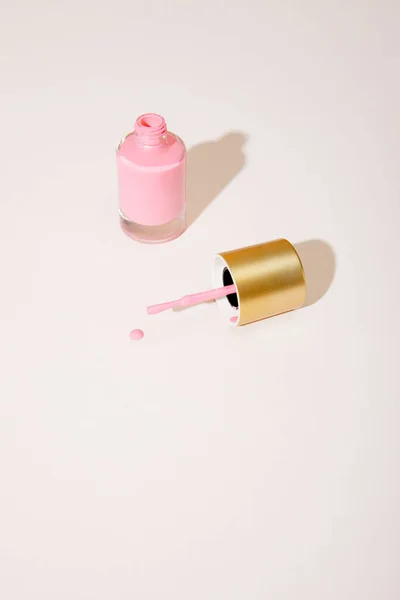Vista de ángulo alto de la botella abierta de esmalte de uñas rosa sobre fondo blanco - foto de stock
