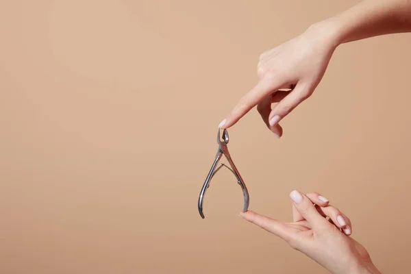 Ausgeschnittene Ansicht einer Frau mit Nagelhautzange isoliert auf beige — Stockfoto