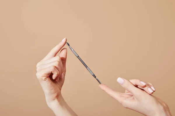 Vue recadrée des mains féminines avec poussoir à cuticules isolé sur beige — Photo de stock