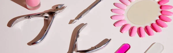 High angle view of samples of nail polish with manicure instruments on white, panoramic shot — Stock Photo