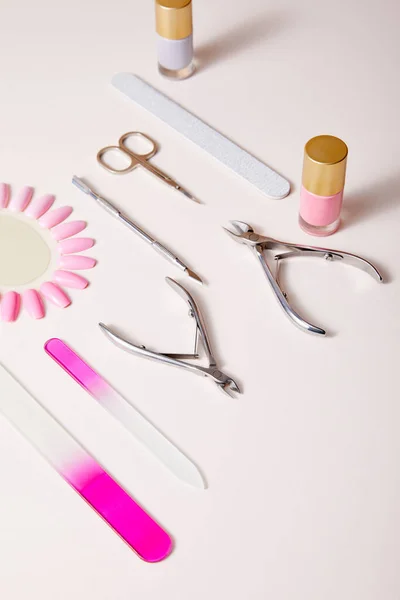High angle view of bottles and samples of nail polish near manicure instruments on white — Stock Photo