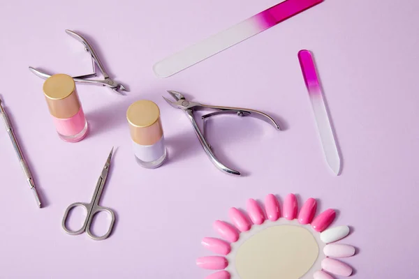 Vista de alto ângulo de garrafas e paleta de esmalte com instrumentos de manicure sobre fundo branco — Fotografia de Stock