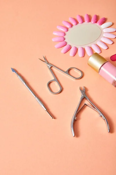 High angle view of bottle and samples of nail polish with manicure instruments on coral background — Stock Photo