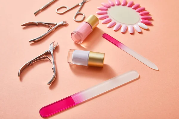 High angle view of bottles and samples of nail polish with manicure instruments on coral — Stock Photo