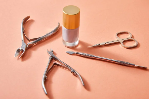 Vista ad alto angolo della bottiglia di smalto bianco con strumenti di manicure su sfondo corallo — Foto stock