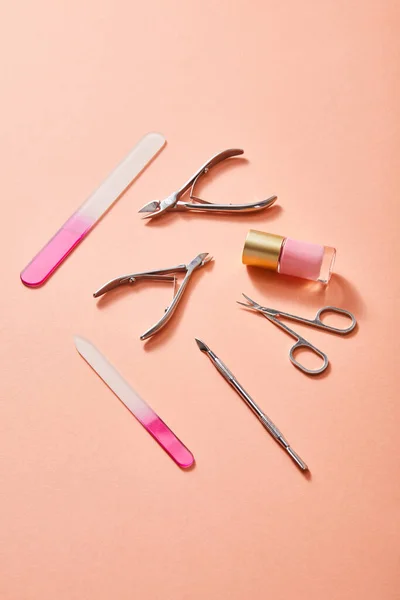 High angle view of bottle of pink nail polish and manicure instruments on coral background — Stock Photo