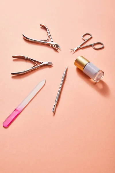 High angle view of bottle of white nail polish and manicure instruments on coral background — Stock Photo