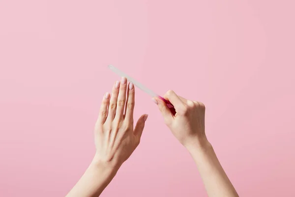 Vue recadrée de la femme classant ongles avec lime à ongles isolé sur rose — Photo de stock