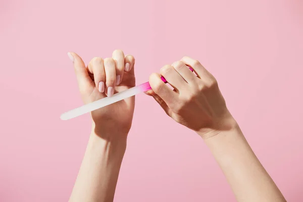 Cropped view of woman filing fingernail with nail file isolated on pink — Stock Photo