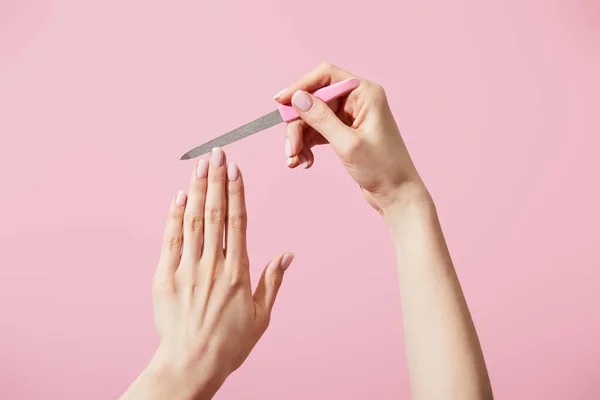 Partial view of woman filing fingernail with nail file isolated on pink — Stock Photo