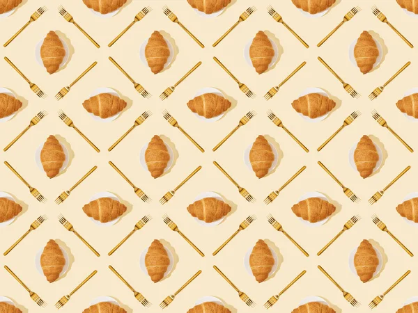 Vue de dessus des fourchettes et croissants dorés sur fond beige, motif sans couture — Photo de stock