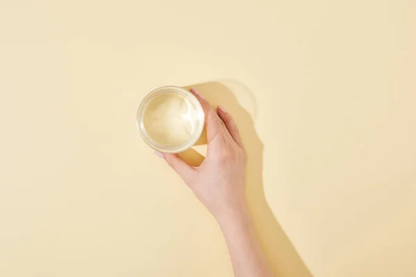 Cropped view of woman holding glass of water on beige background — Stock Photo