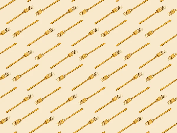 Top view of golden forks isolated on beige, seamless background pattern — Stock Photo