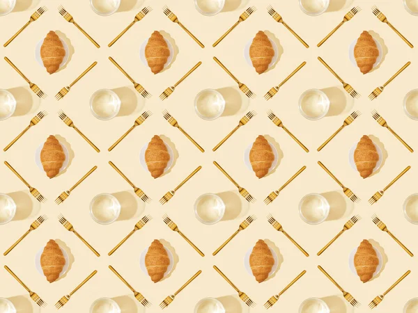 Ansicht von goldenen Gabeln, Wassergläsern und Croissants auf beigem, nahtlosem Hintergrundmuster — Stockfoto