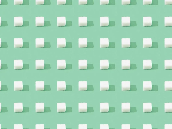 Top view of lump sugar on green, seamless background pattern — Stock Photo