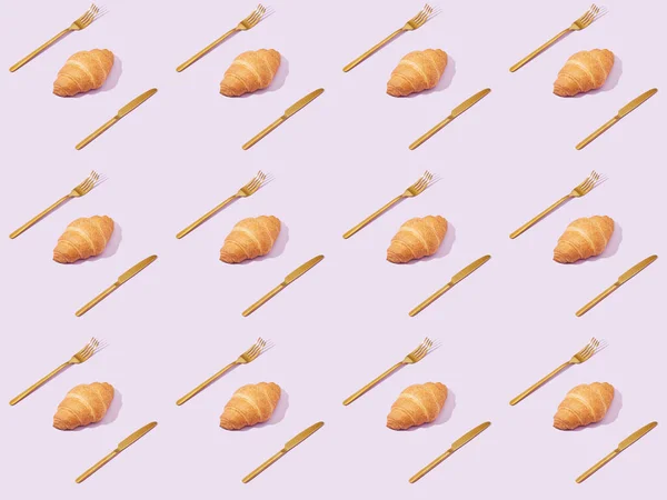 Golden forks and knives with croissants isolated on violet, seamless background pattern — Stock Photo