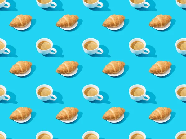 Свежие круассаны на тарелках и кофе на голубом, бесшовном фоне — стоковое фото