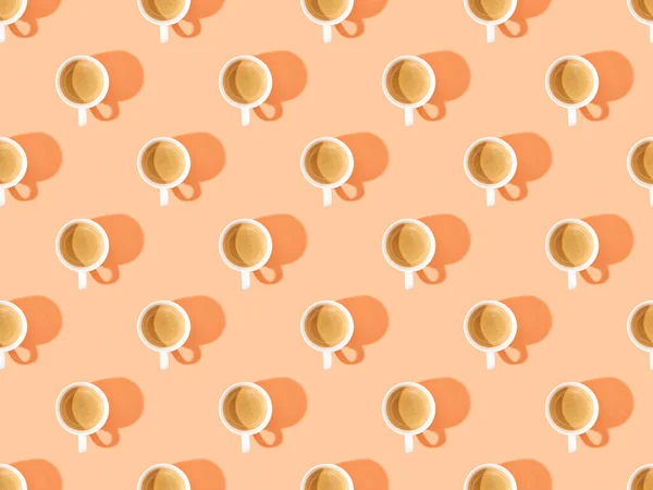 Top view of cups of fresh coffee on orange, seamless background pattern — Stock Photo