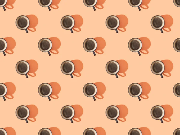 Top view of cups of fresh coffee on orange, seamless background pattern — Stock Photo