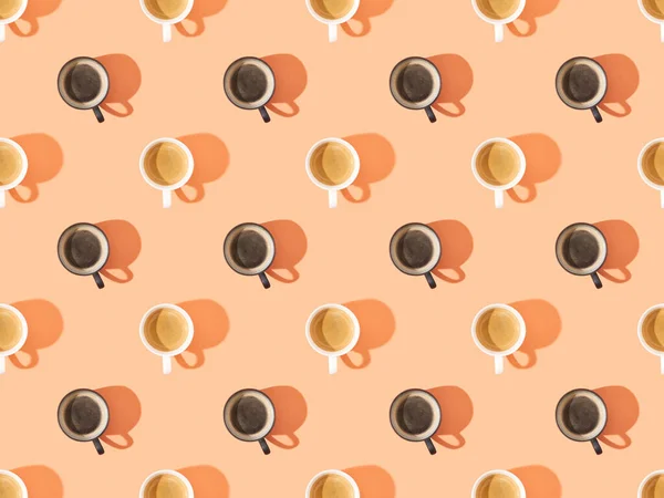 Vista superior de tazas de café fresco en naranja, patrón de fondo sin costuras - foto de stock