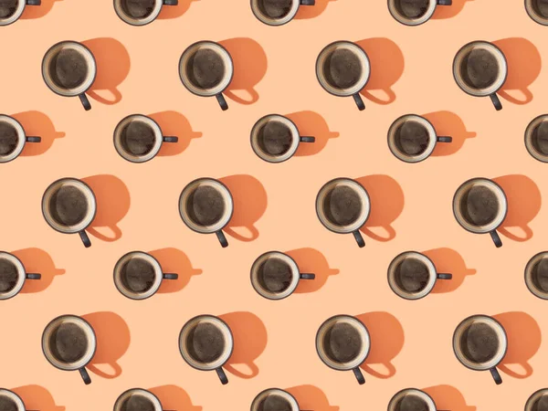 Top view of cups of fresh coffee on orange, seamless background pattern — Stock Photo