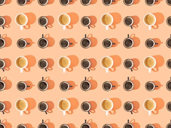 Top view of cups of fresh coffee on orange, seamless background pattern — Stock Photo