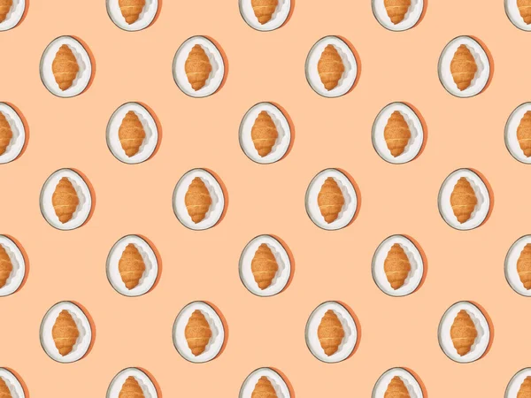 Top view of fresh croissants on plates on orange, seamless background pattern — Stock Photo