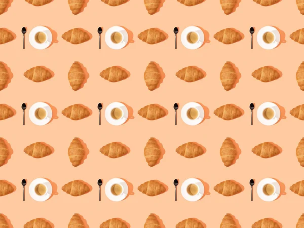 Vue de dessus des cuillères, croissants frais sur assiettes et café sur orange, motif de fond sans couture — Photo de stock