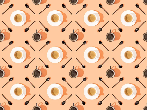 Vista dall'alto di tazze di caffè fresco su piatti e cucchiai su arancione, modello di sfondo senza soluzione di continuità — Stock Photo