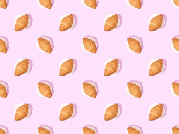 Draufsicht auf Croissants auf Tellern auf rosa, nahtlosem Hintergrundmuster — Stockfoto