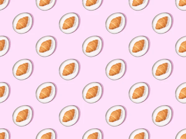 Top view of croissants on plates on pink, seamless background pattern — Stock Photo