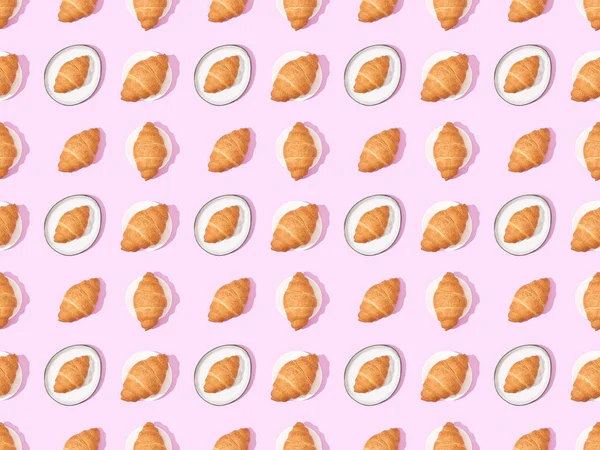Top view of croissants on plates on pink, seamless background pattern — Stock Photo