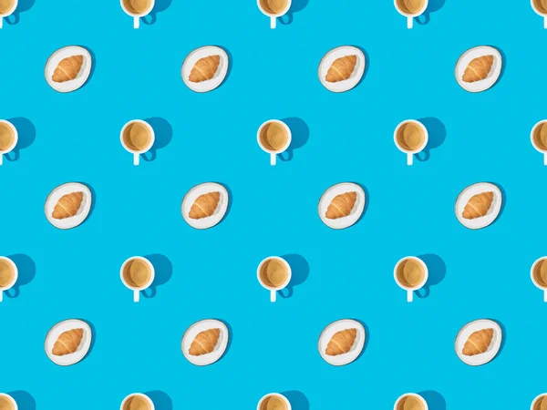 Top view of croissants on plates and coffee on blue, seamless background pattern — Stock Photo