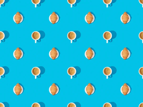 Top view of croissants on plates and coffee on blue, seamless background pattern — Stock Photo