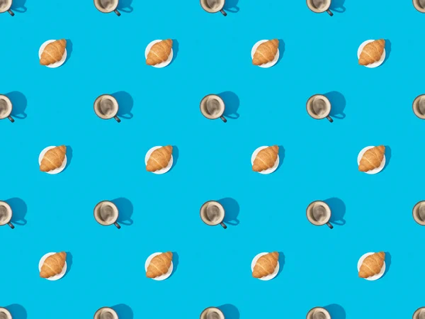 Top view of croissants on plates and coffee on blue, seamless background pattern — Stock Photo