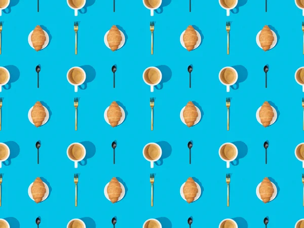 Top view of cutlery, croissants on plates and coffee on blue, seamless background pattern — Stock Photo