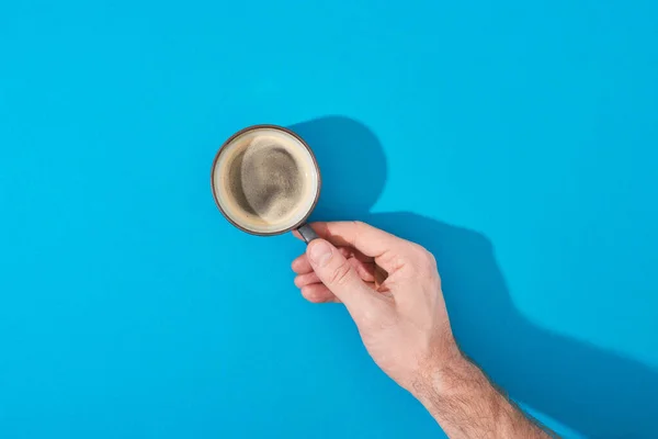 Cropped view of man holding cup of fresh coffee on blue background — Stock Photo