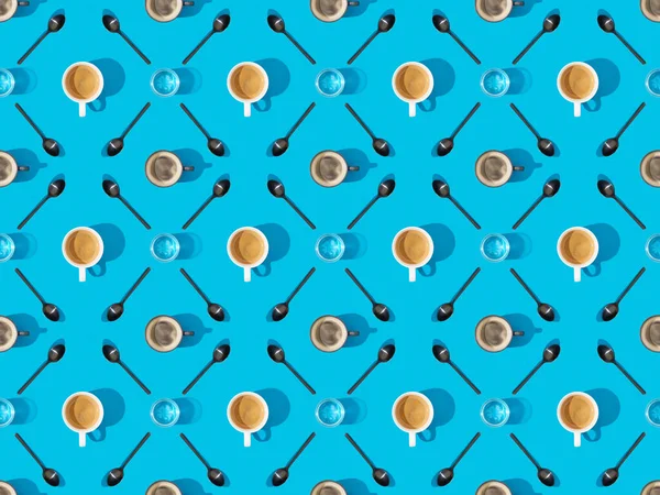 Top view of cups of fresh coffee, spoons and glasses of water on blue, seamless background pattern — Stock Photo