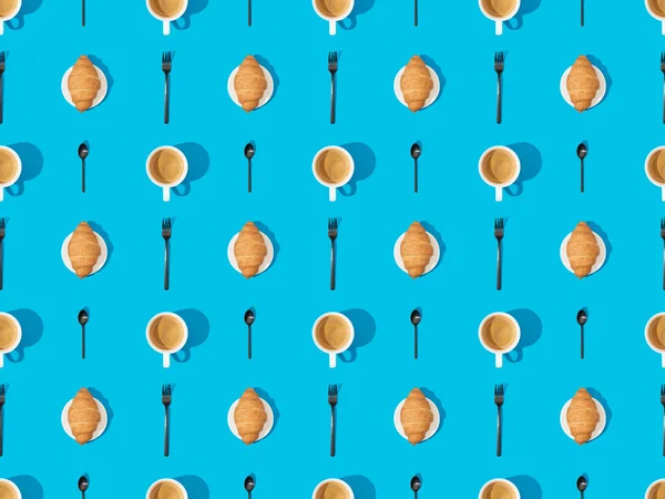 Ansicht von Besteck, Croissants auf Tellern und Kaffee auf blauem, nahtlosem Hintergrundmuster — Stockfoto