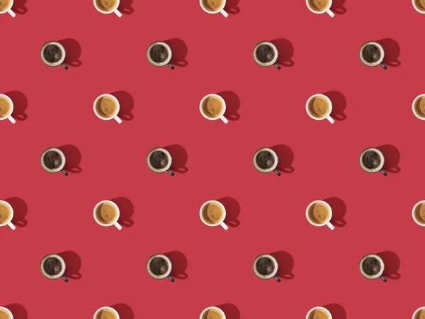 Top view of cups of fresh coffee on red, seamless background pattern — Stock Photo