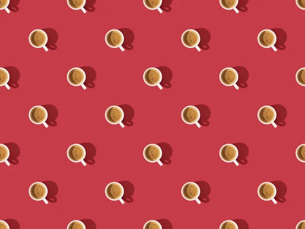 Top view of cups of fresh coffee on red, seamless background pattern — Stock Photo