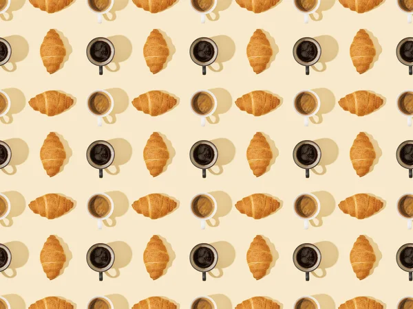 Top view of croissants and coffee on beige, seamless background pattern — Stock Photo