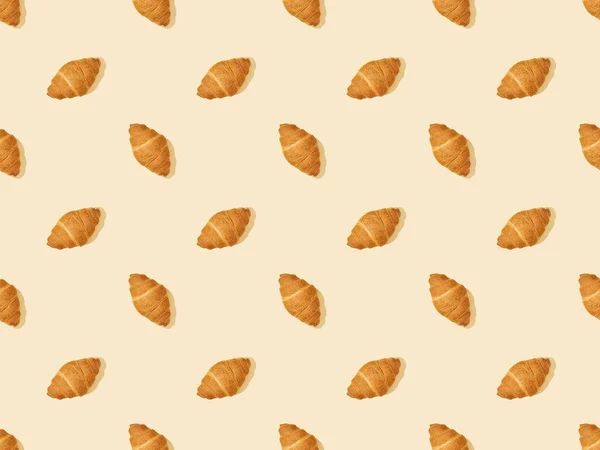 Top view of fresh croissants on beige, seamless background pattern — Stock Photo