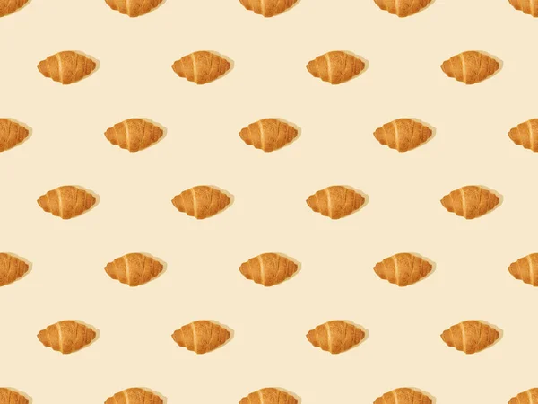 Vue de dessus des croissants frais sur beige, motif de fond sans couture — Photo de stock