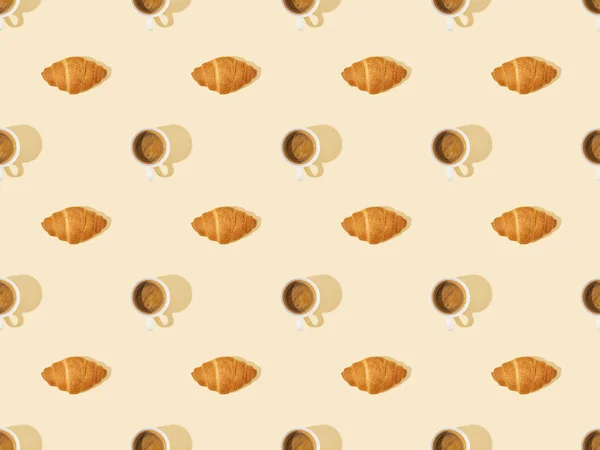 Top view of croissants and coffee on beige, seamless background pattern — Stock Photo